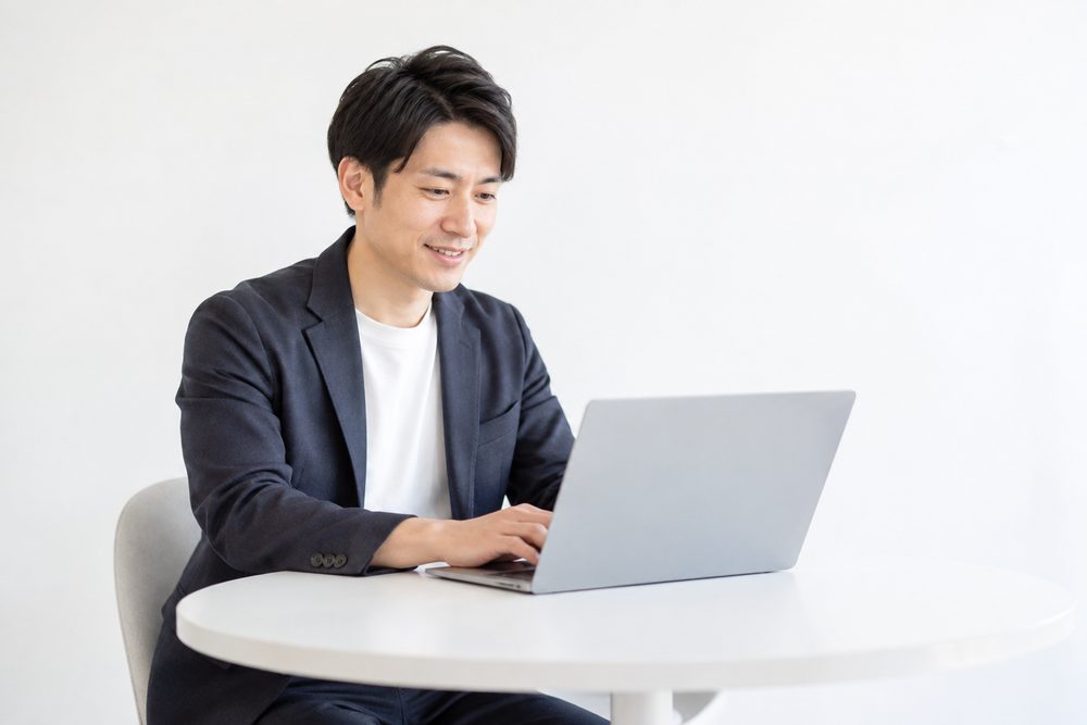 ノートパソコンで資料を開いて、ほほえむ人
